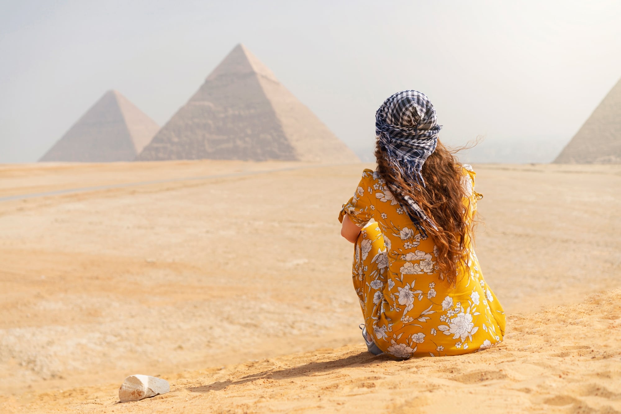 Woman looks at pyramids in the distance
